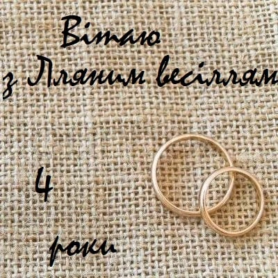 Два золоті кільця на льоні з привітанням до четвертого весільної річниці.