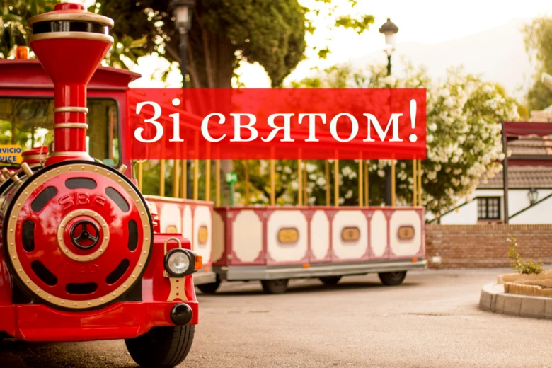Червоний мініатюрний потяг на коліях з привітанням.