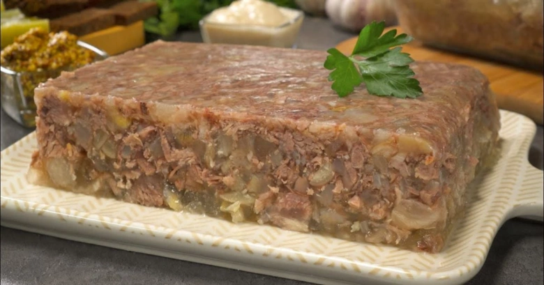 Готовий холодець з м'ясом та овочами на тарілці.