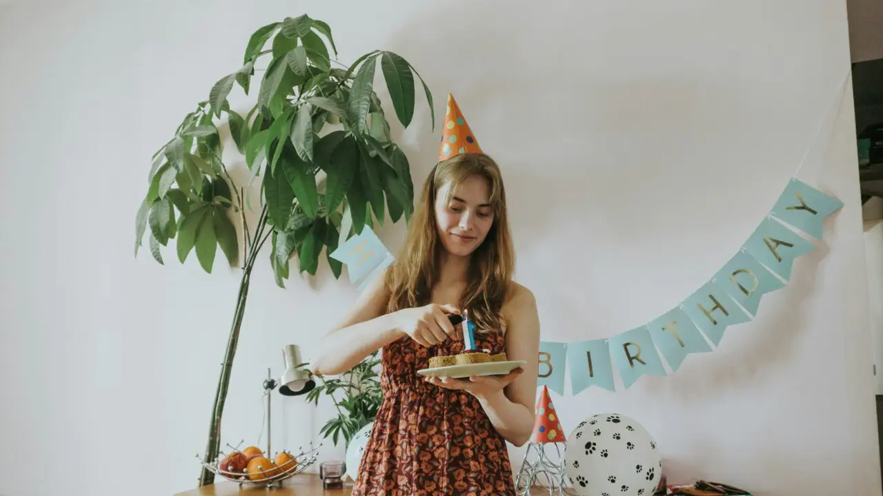 Жінка вітається з днем народження, різьблячи торт.