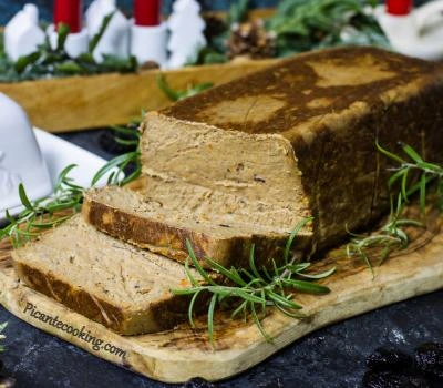 Січений м'ясний паштет з гілочками розмарину на деревній дошці.