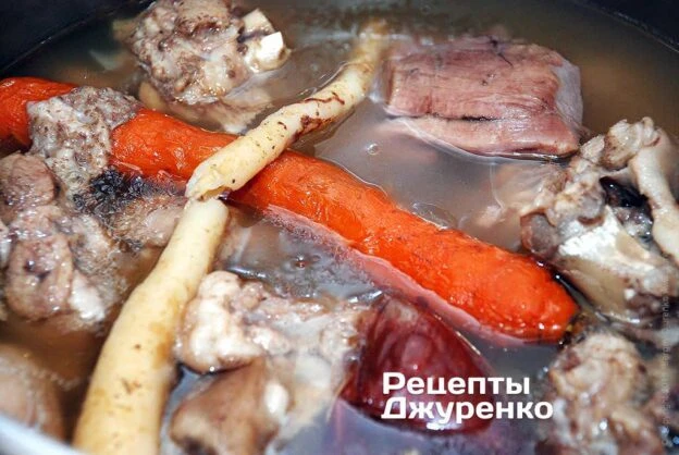 Куски м'яса та моркви варяться в бульйоні для холодецю.