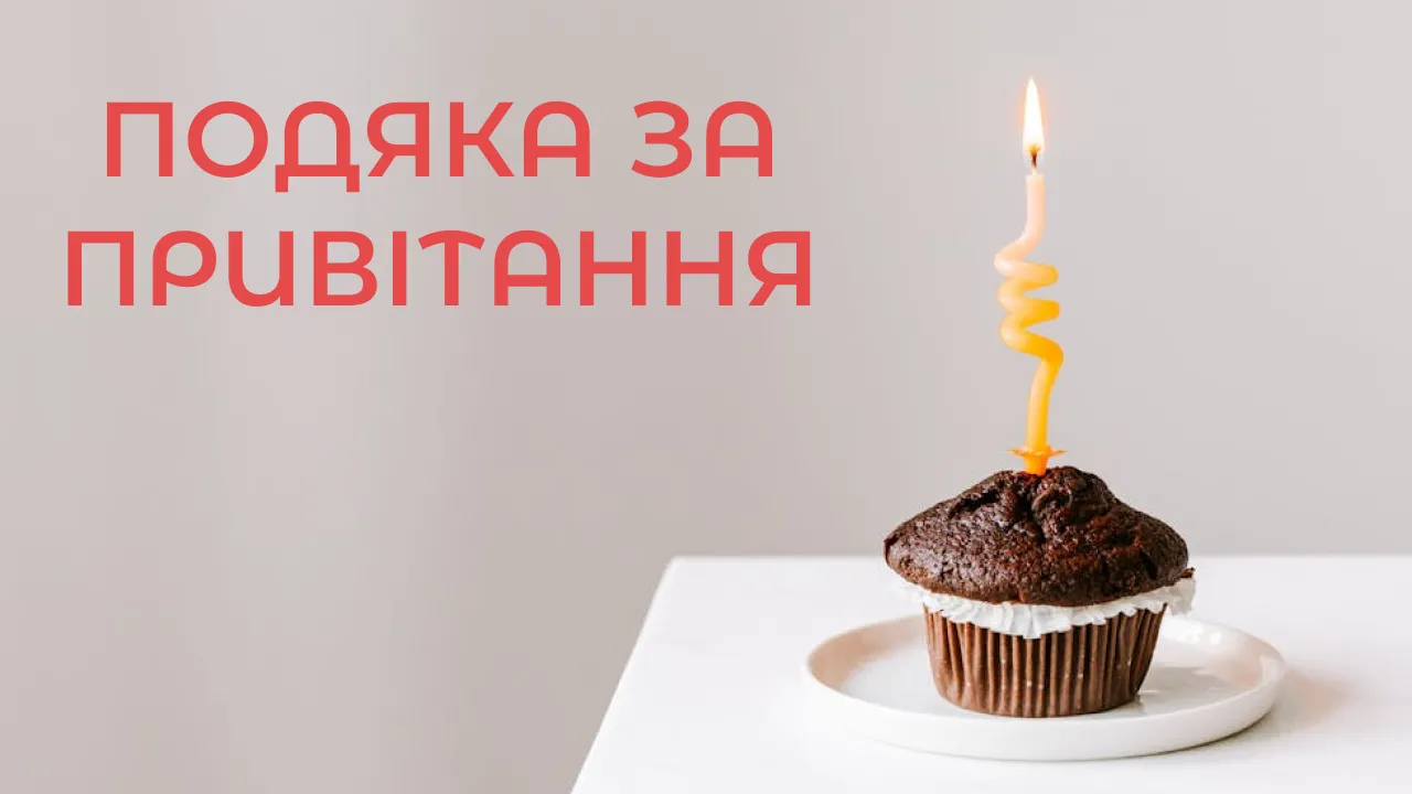 Шоколадний кекс із запаленою свічкою та привітанням.