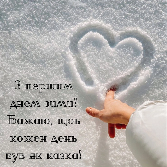 Рука малює серце у снігу з привітанням на перший день зими.