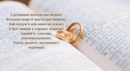 Два золоті кільця на відкритій книзі з привітанням.